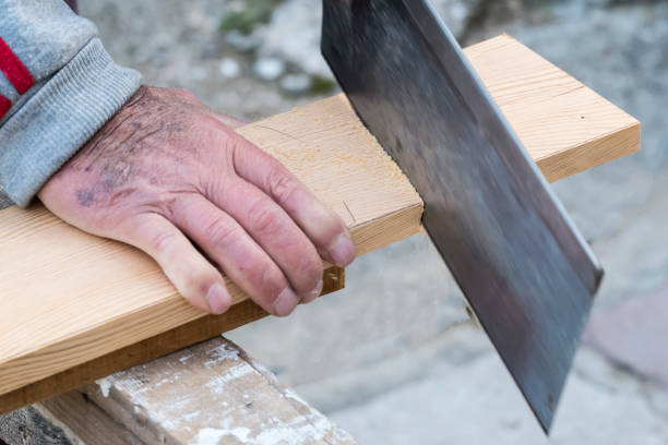 istock Carpenter sawing a board with a hand wood saw 1201392205