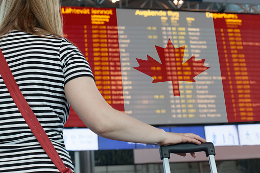 Una mujer mira el marcador en el aeropuerto. Seleccione un país Canadá para viajes o migración. photo