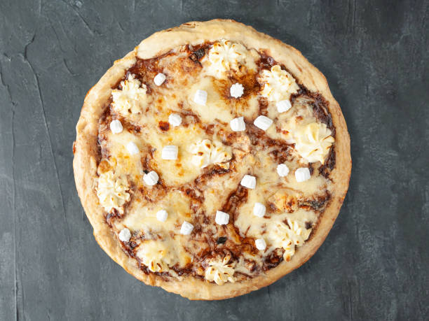istock Sweet pizza with chocolate paste Nutella, banana, cream cheese, Mozzarella cheese, Sulguni, marshmallows. Wide side. View from above. On a gray concrete background. Isolated. 1201393513