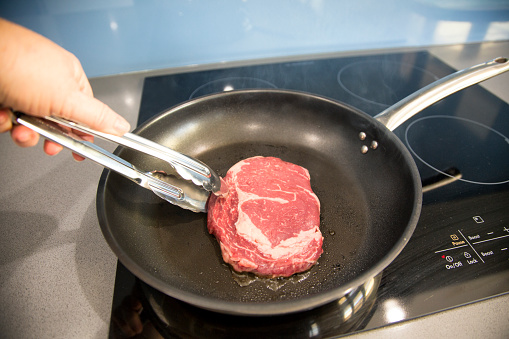 Scotch Fillet steak cooking in a frying pan. Australia.