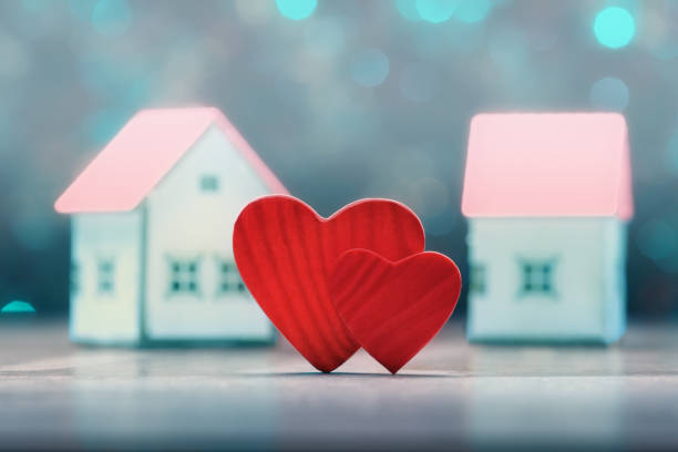 istock Two hearts over blur house models and defocused lights. Valentine's day concept 1201396516