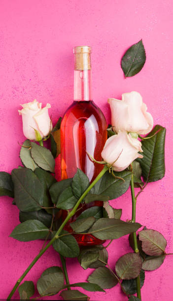 wine with white fresh roses on a pink background. vertical image - pink rose flower color image imagens e fotografias de stock