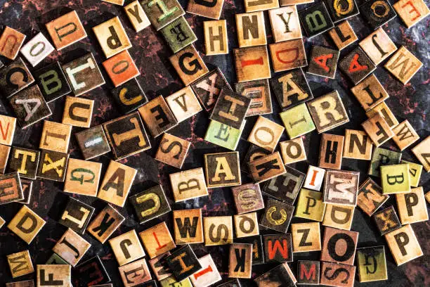 Photo of Colored alphabet tiles scattered across rusted metal surface