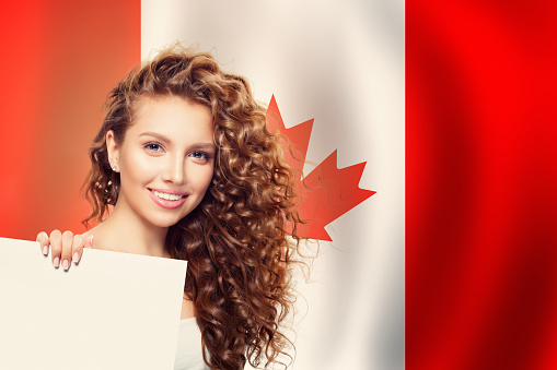 Happy young woman showing white paper against the Canada flag background. Live, work, education and internship in Canada