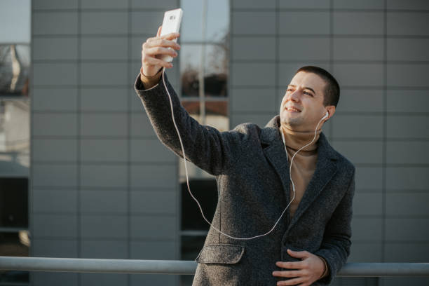istock Elegant young man is using smartphone outside 1201402858