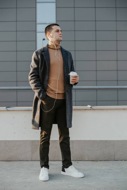 istock Young man in front of a modern building is drinking coffee to go 1201402909