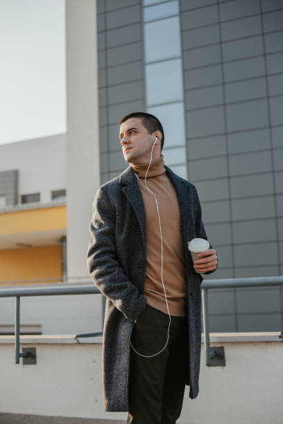 istock Young man in front of a modern building is drinking coffee to go 1201403806