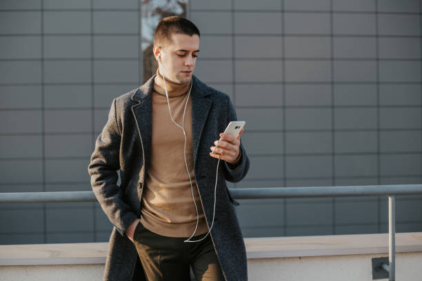 istock Elegantly dressed man is using mobile phone in front of modern building 1201404276