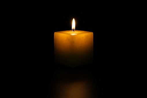 Lighted candle, on neutral black background, ideal for text overlay