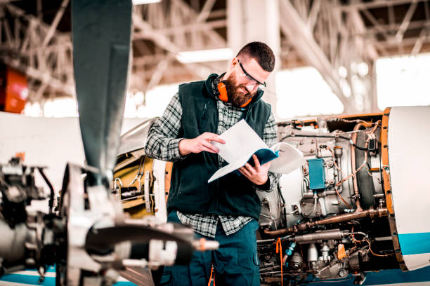 istock Aircraft technician going through a manual while performing service in a maintenance hangar 1201406065