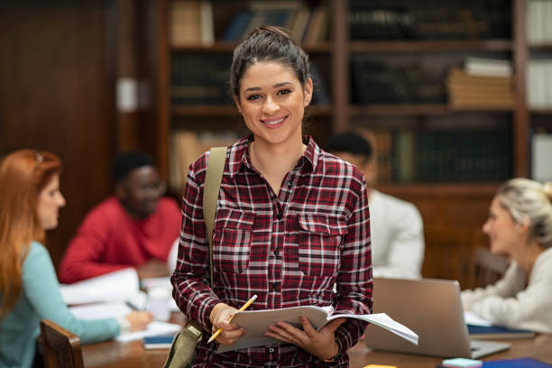 estudante sorridente na biblioteca - library student latin american and hispanic ethnicity university - fotografias e filmes do acervo