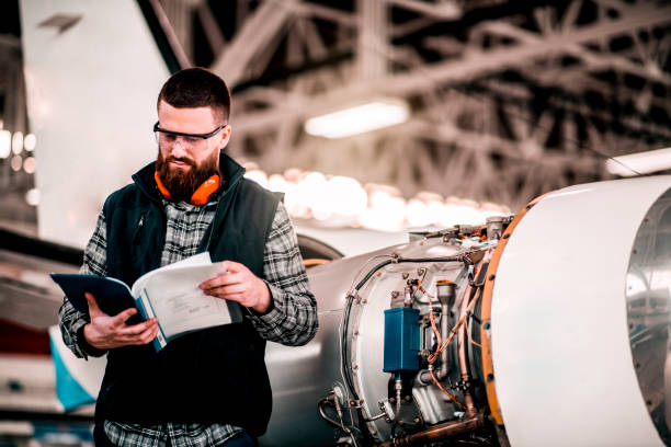 istock Aircraft engineer reading a maintenance instructions in an airplane hangar while working on an airplane 1201407208