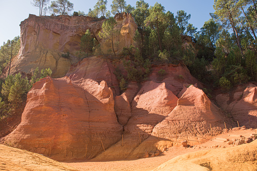 Ochre Trail in Roussillon, Sentier des Ocres, hiking path in a natural colorful area of red and yellow cliffs surrounded by green forest in Provence