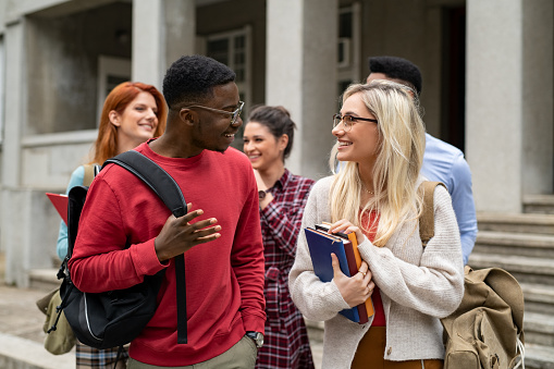Amigos estudiantes multiétnicos caminando en el campus universitario photo