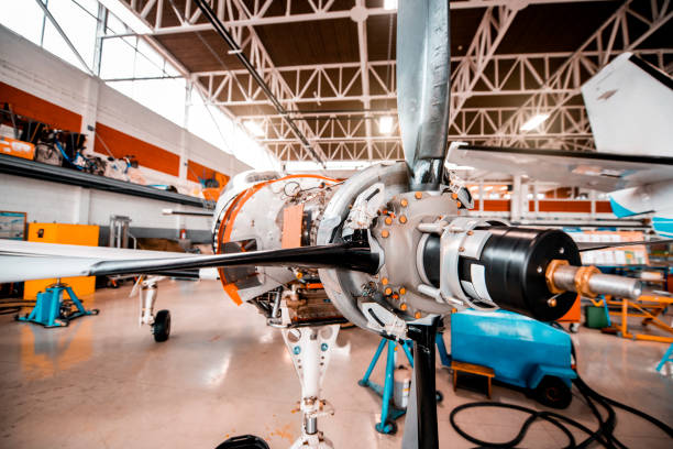 Partially disassembled small propeller airplane with opened motor compartment in a maintenance hangar.