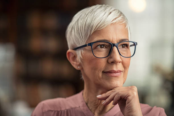 mature woman thinking - professor librarian university library imagens e fotografias de stock