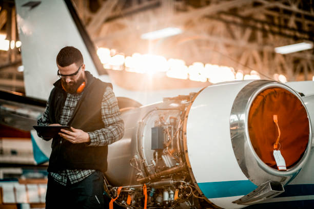 istock Aircraft engineer in a hangar holding a digital tablet while repairing and maintaining an airplane jet engine 1201407805