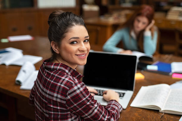 giovane studente che lavora su laptop in biblioteca - library student latin american and hispanic ethnicity university foto e immagini stock