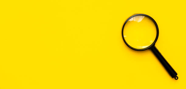 istock Close up magnifier glass on yellow background. View from above. 1201409603