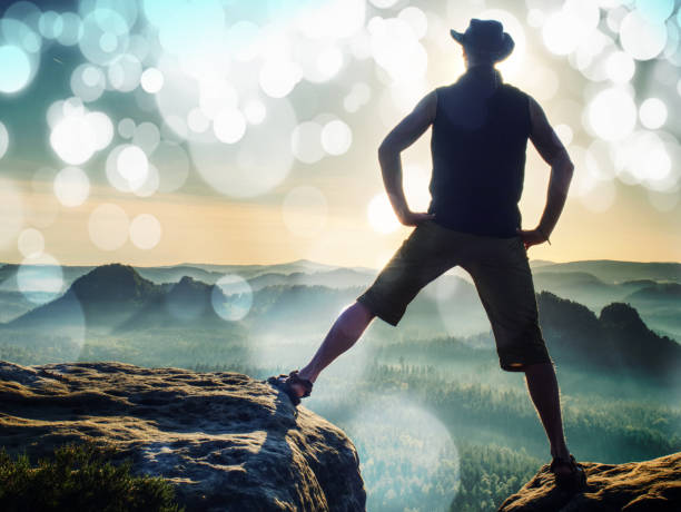 istock Lone figure watches the sunset from sharp rock looking down 1201410172