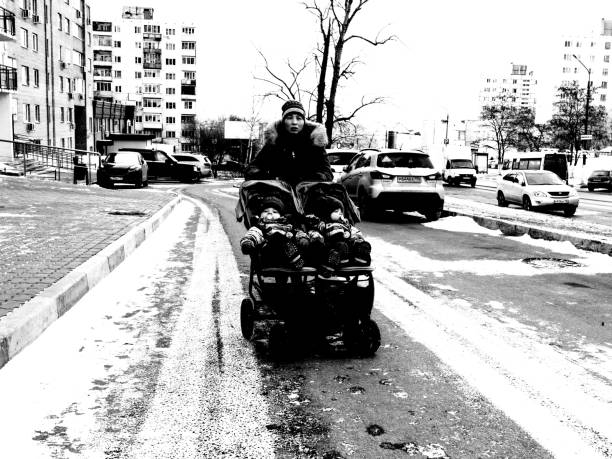 Moscow, Russia - January 23, 2020: an asian woman is pushing a twin baby carriage