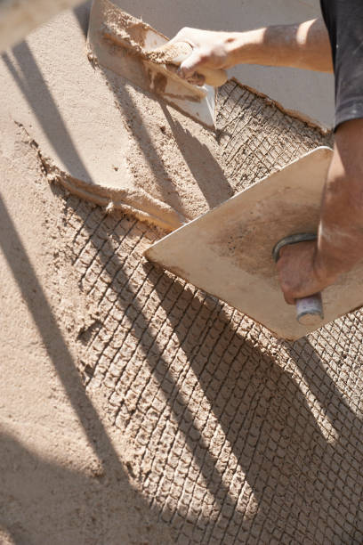istock Man using trowel to plaster outside wall of house 1201412070