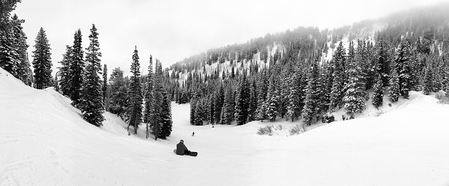 View of the slopes of Solitude ski resort with a sitting snowboarder.