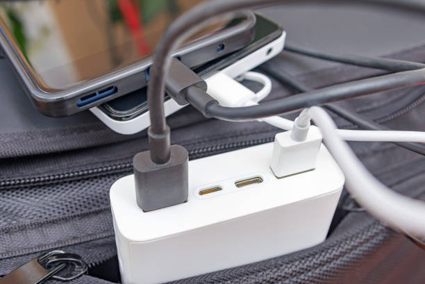 トラベルバッグにパワーバンクで充電するスマートフォン。選択的な焦点。 - mobile phone charging power plug adapter ストックフォトと画像