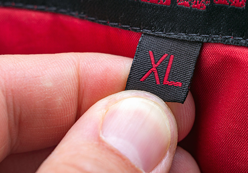 Mano del hombre sostiene la etiqueta de la etiqueta de la ropa del tamaño XL. La elección de la ropa por tamaño, concepto. photo