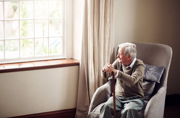 A time to pause and reflect Shot of a senior man looking thoughtfully out of a window at home fragility stock pictures, royalty-free photos & images