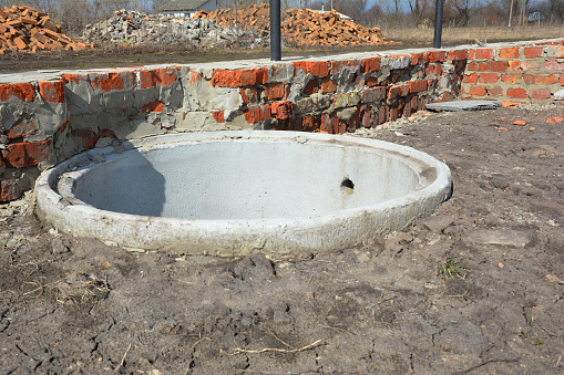 Installing concrete septic tank. Sewer tank hole installation outdoors