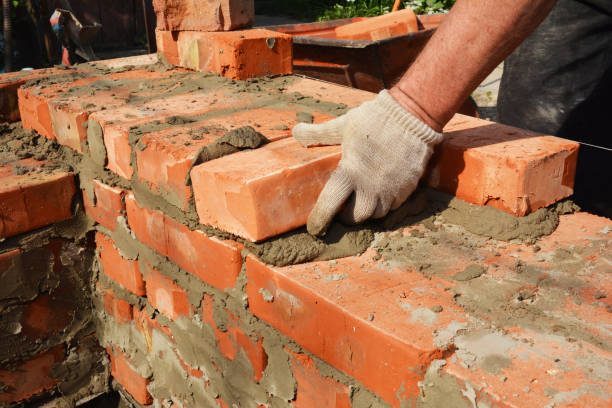 istock Bricklayers hands in masonry gloves bricklaying house wall. Bricklaying, Masonry, Brickwork close-up 1201414226