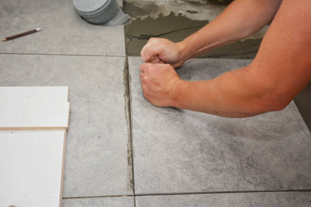 istock Bathroom flooring works. Worker installing ceramic tile on the floor. 1201414387