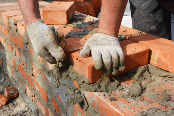 istock Bricklayer hands in masonry gloves bricklaying new house brick wall. Masonry close up. 1201414543