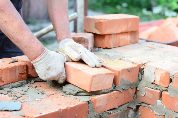 istock Bricklaying house wall,  masonry. Bricklayer hands in masonry gloves bricklaying house wall. 1201415349