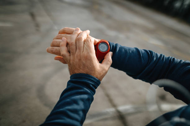 mature men running and using smart watch outdoors - playing field determination exercising relaxation exercise imagens e fotografias de stock