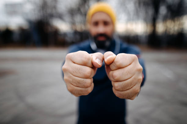 Mature bearded man with knit hat stretching before exercise outdoors, focus on hands