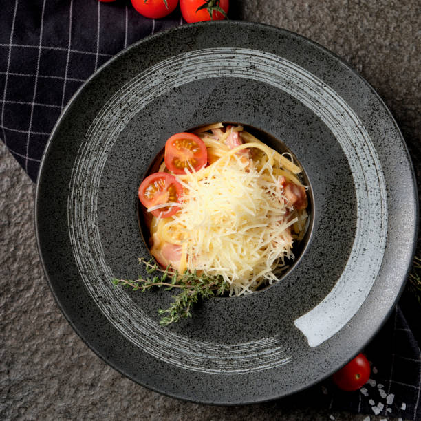 istock Top view Carbonara paste with Parmesan cheese, bacon, cherry tomatoes bunch and sauce on a plate on napkin, stone background. 1201416215