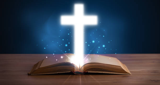 istock Open holy bible with glowing cross in the middle 1201417286
