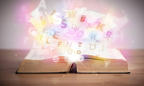istock Open book with glowing letters on concrete background 1201417636