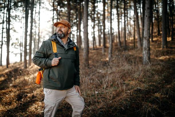 Mature male backpacker climbing a mountain and looking at beautiful nature behind him