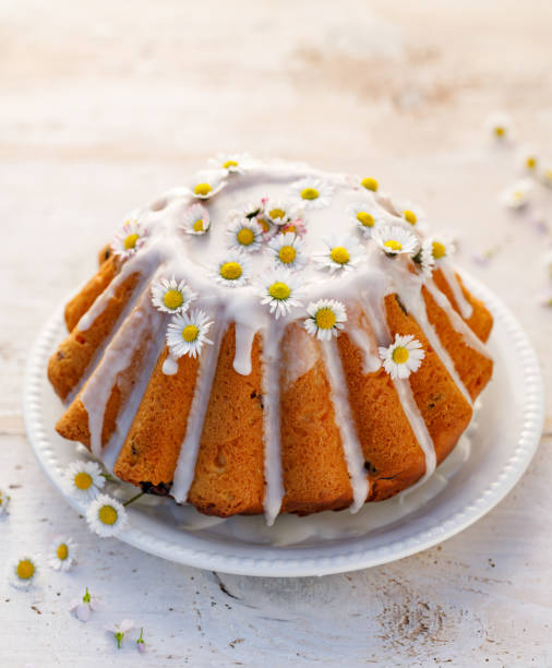istock Easter yeast cake (Babka) covered with icing and decorated with daisies on a white plate on a white wooden table. 1201422039