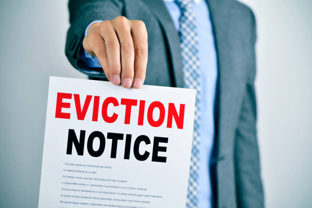 man with an eviction notice a young caucasian man wearing a gray suit shows a document with the text eviction notice eviction photos stock pictures, royalty-free photos & images