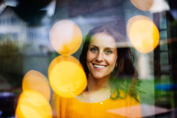 istock Young woman sitting laughing behind a window 1201429371