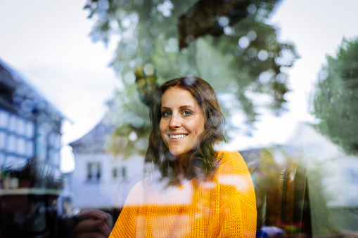 Young woman sitting laughing behind a window.