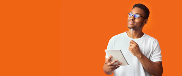 pensive black guy portrait on orange background - made man object imagens e fotografias de stock