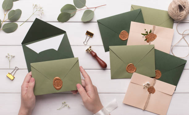 istock Woman making wedding envelopes with invitations on white 1201431084