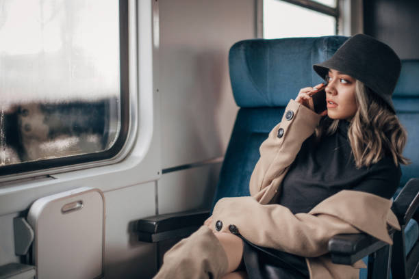 istock One young woman with hat talking on the mobile phone in train 1201431513
