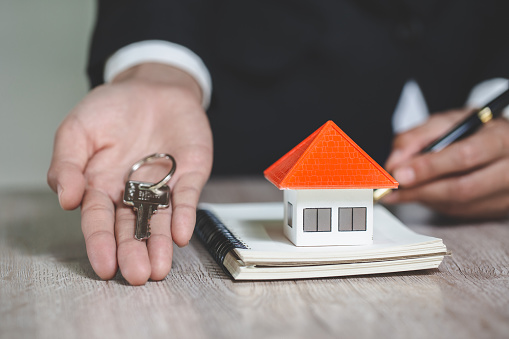 real estate agent holding house key to his client after signing contract agreement in office,concept for real estate, renting property