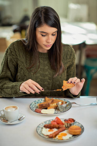 istock Attractive brunette sitting in restaurant in morning and eating breakfast. 1201431824